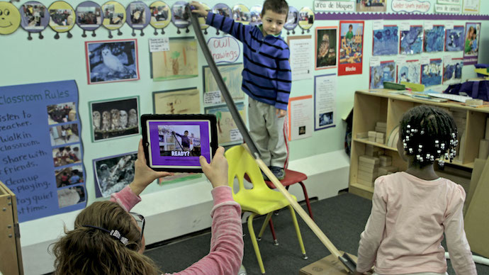 A teacher using the app to film preschool children releasing a ball down a tall ramp.