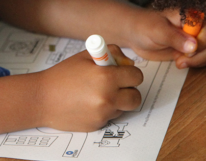 A young girl uses a marker as she navigates a maze on paper.