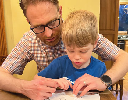 A father and his child look together at a world map.