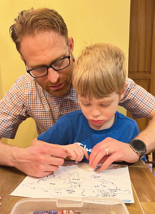 A father and his child look together at a world map.