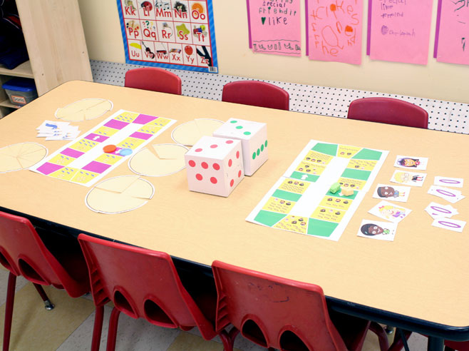 The Park Play Board Game is set up on a table with six red chairs in a preschool classroom.