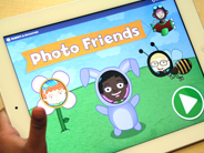 Close-up of a child’s hands holding an iPad with the Gracie and Friends Photo Friends app on-screen.