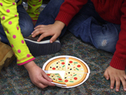 A child arranges four pieces of a paper pizza.