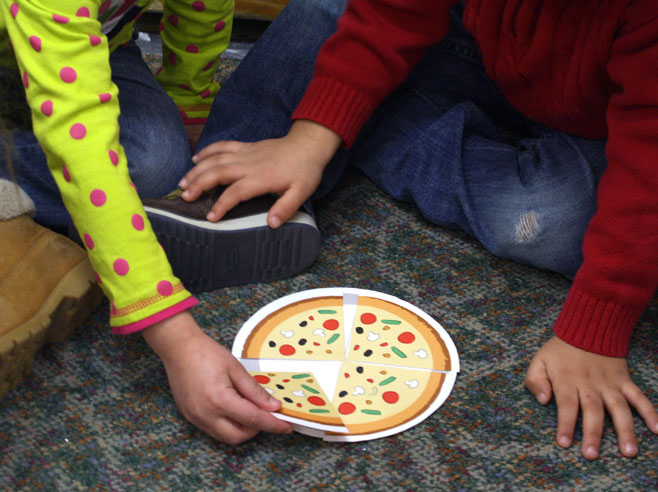 A child arranges four pieces of a paper pizza.