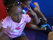 A girl holds up two fingers on each hand during a game of Two Red Apples.