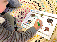 A boy draws a pathway between landmarks on a farm scene.