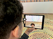 A man views a digital fair scene through an iPad as he plays the Gracie & Friends “AR Adventures” augmented reality app.