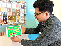 A man models playing farm map game in the Gracie & Friends “Map Adventures” preschool spatial thinking app.