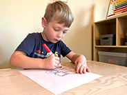 A boy draws a map on a piece of paper with a marker.