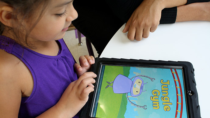 A young child in a purple shirt looks at the Early Math with Gracie & Friends Jungle Gym app while a grown-up sits close by.