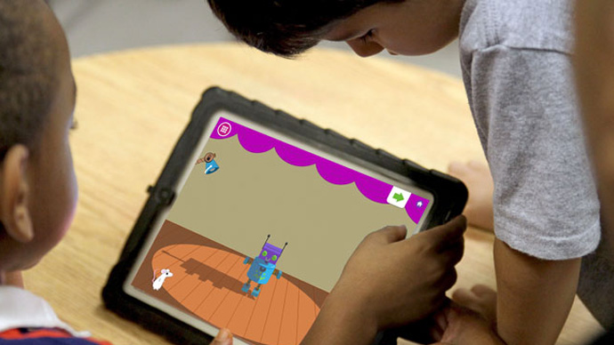 Two preschool boys playing the Shadow Play app by shining lights on a robot.