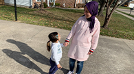 Parent and child making shadows while holding hands outside.