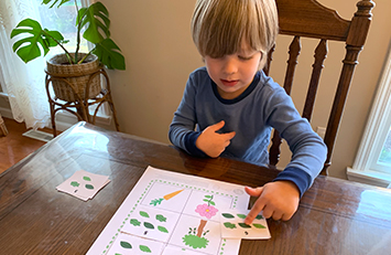 Child placing a card on a game board.