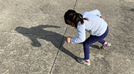 Child making a shadow while posing outside.