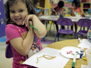 Student smiles next to her art project.
