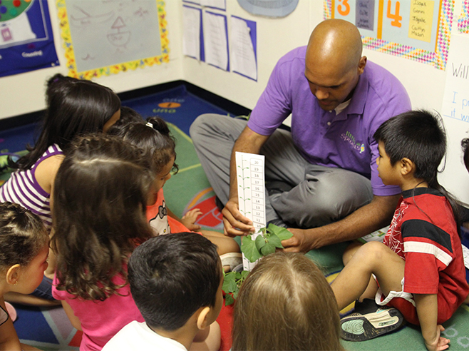 Teacher shows students how to measure a plant.