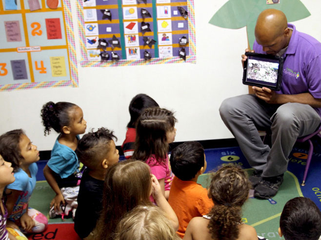 Teacher shows students 'Exploring Small Spaces' video on iPad.
