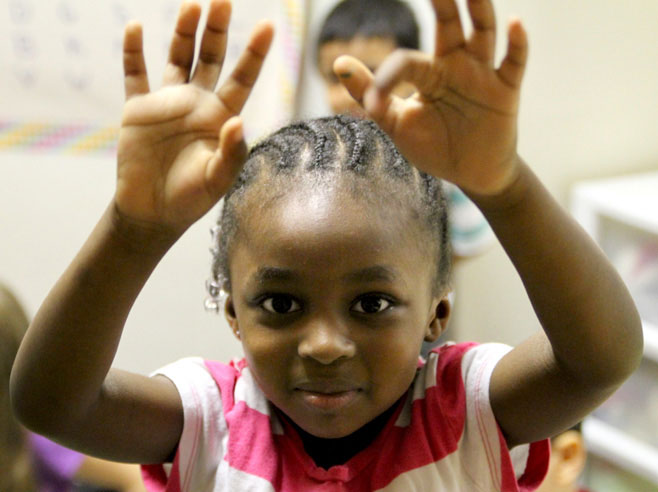 Student holds hands above her head.