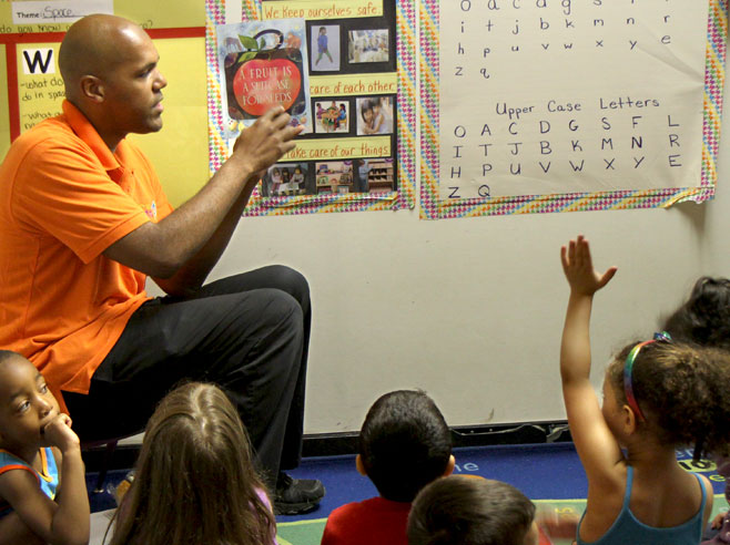 Teacher holds up the book 'A Fruit is a Suitcase for Seeds'