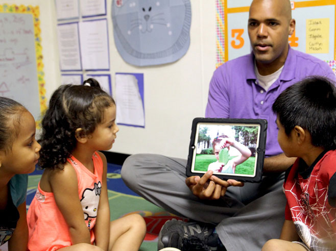 Teacher shows students scavenger hunt pictures in app.