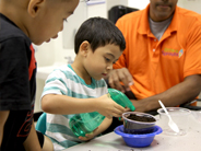 A student waters a plant in classroom.