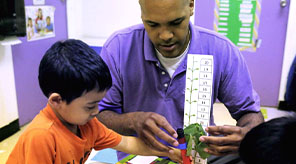 A teacher and student measuring a plant.