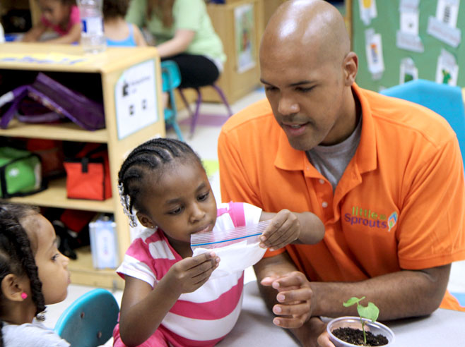 Teacher and student examine bean plant.