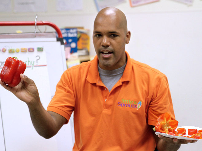 Teacher holds up a full pepper and a pepper cut up into pieces on a plate.
