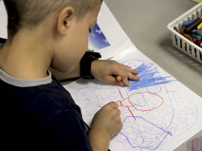 A boy drawing with crayons.