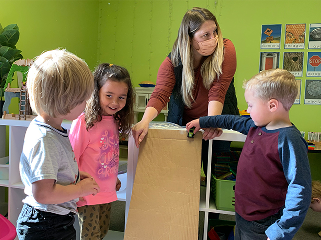 Teacher and students test a cardboard ramp.