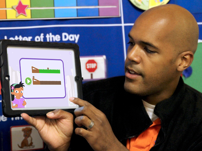 Teacher holds up Coconut Canyon app on iPad.