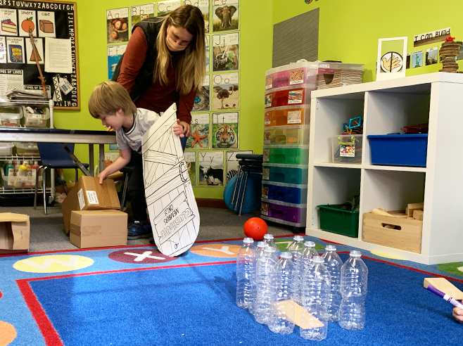 Student and teacher build a cardboard ramp.