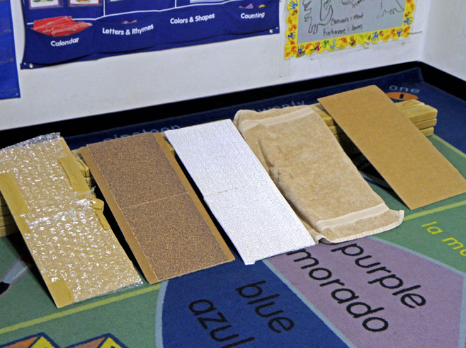 Five cardboard ramps covered in different textured materials.