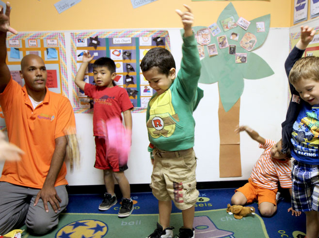 Students and teacher hold hands in the air, during a song about gravity.