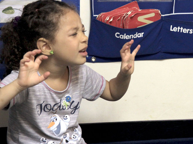 A student with her eyes closed gives herself an imaginary push down a slide.