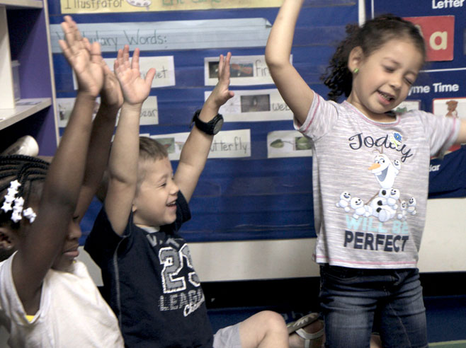 Students close their eyes and wave their arms in the air.