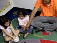 During circle time, one student gets ready to push a baseball across the floor.