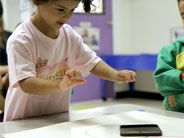 A student pushes a plastic lid across a table.