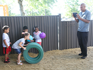 Teacher records student rolling a tire outside.