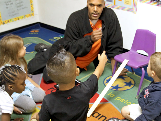 Teacher talking with students after rolling a marble down a ramp.