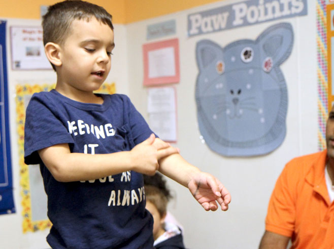 A student demonstrates ladder climbing motion, using his fingers on his own arm.