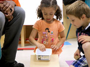 A student prepares to release a plastic tub down a cardboard ramp.
