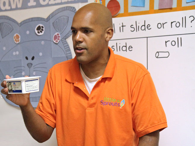 A teacher holds up a plastic carton.