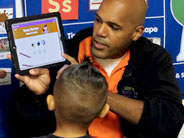 A teacher holds an iPad up and points to the screen. Students look on.