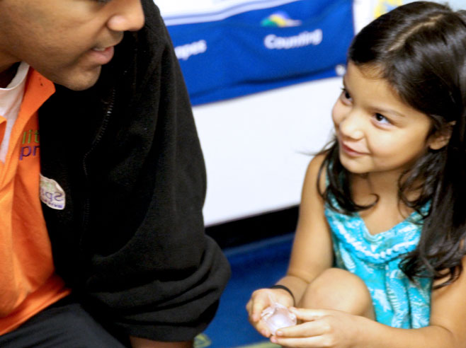 A student looks up at the teacher, as she holds an ice cube in her hands.