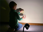 Light shining on student holding two circles to make shadows on the wall.
