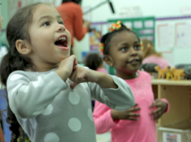 Two students sing and make gestures with their arms.