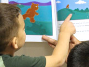 A student points at an illustration in the book, 'Moonbear’s Shadow'.