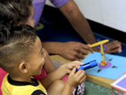 Students and a teacher are setting up a rotation station, a piece of card with a colored circle in the middle, and arrows pointing in four directions, N, S, E, and W. One student holds a flashlight.