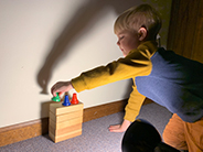 Light shining on student stacking items on a stack of blocks.